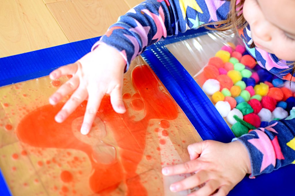 kisgyermek játszik egy érzékszervi táska tele olajjal, vízzel